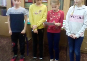 Zdjęcie przedstawia grupę czworga uczniów z IIIa czytających wybrany wiersz z książki "Nasz teatrzyk".